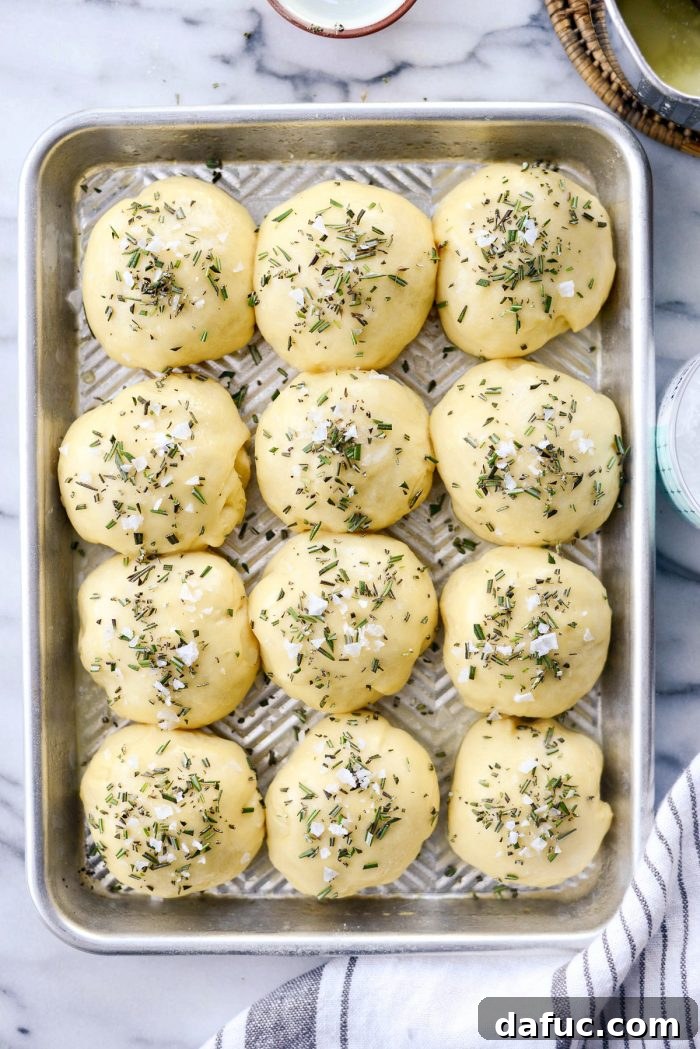 Close-up of buttered dinner rolls, ready for the rosemary and sea salt topping.