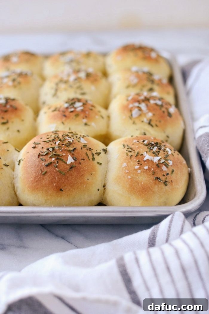 Sprinkling minced fresh rosemary and flaky sea salt onto buttered dinner rolls.