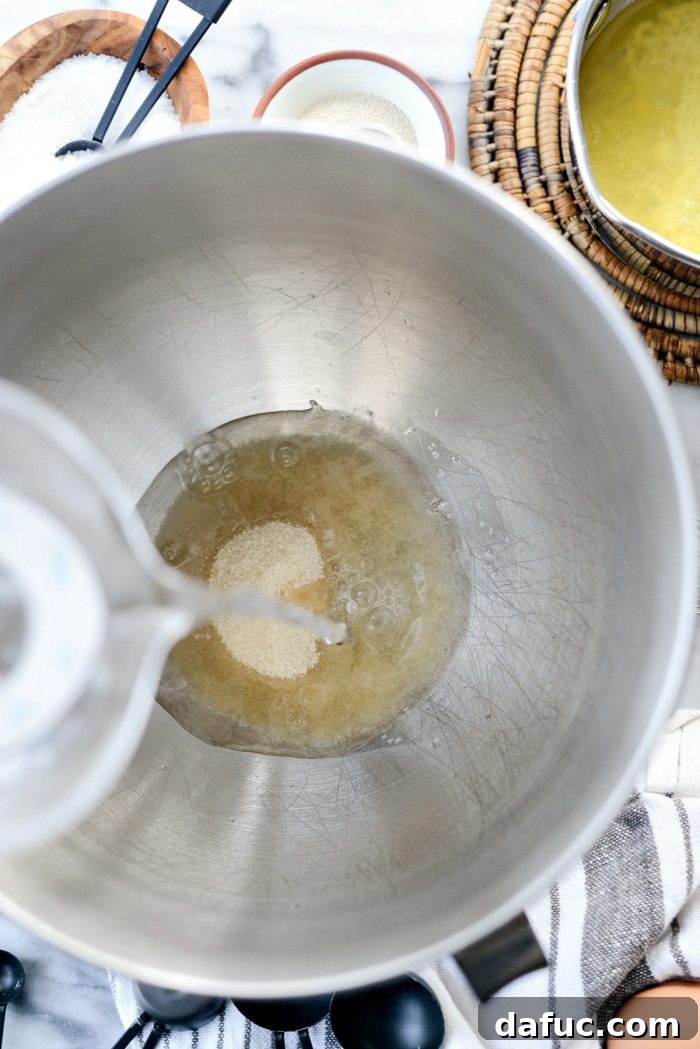 Measuring ingredients for homemade Sea Salt Rosemary Dinner Rolls, highlighting sugar, water, and yeast.