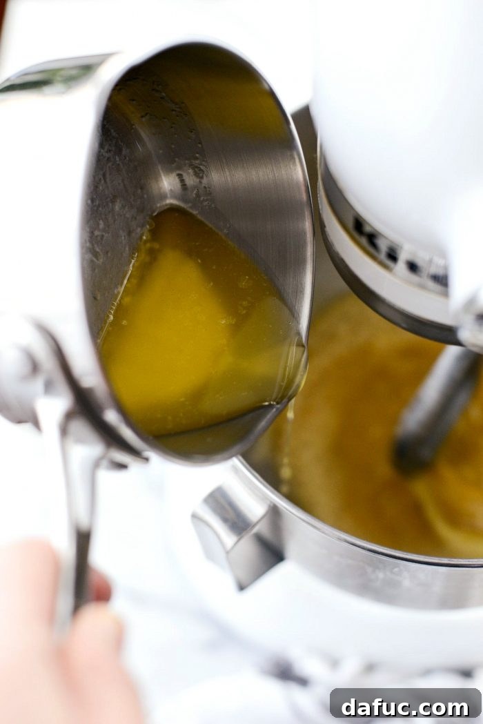 Adding eggs one by one to the yeast mixture in a stand mixer with a paddle attachment.