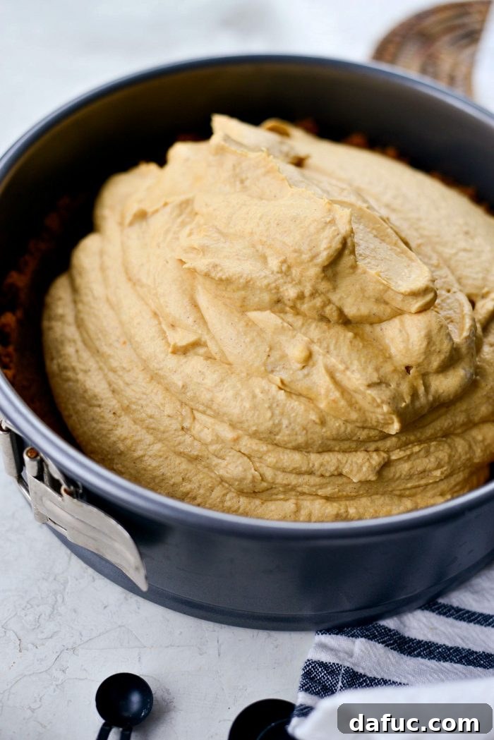 Dreamy No-Bake Pumpkin Cheesecake with a Gingersnap Crunch 15 Pouring Pumpkin Cheesecake Filling into Gingersnap Crust