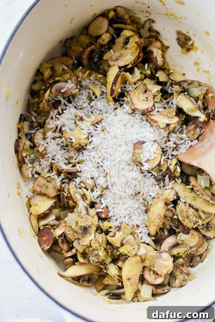 Adding long-grain white rice to the roux and mushroom mixture, before pouring in liquids