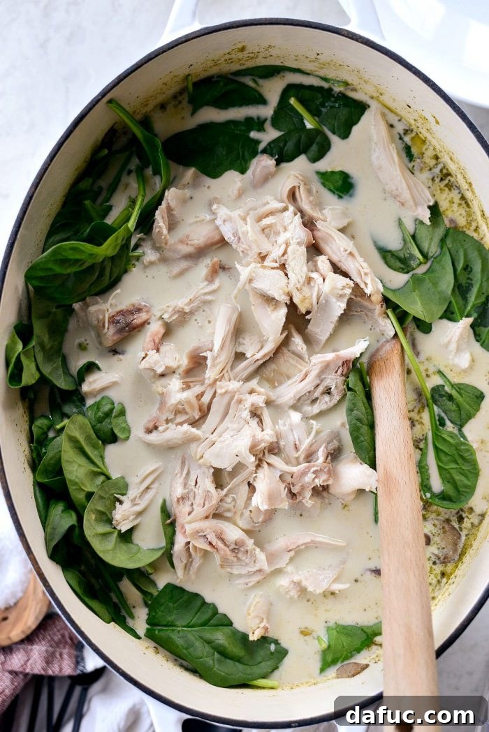 Adding fresh baby spinach and shredded cooked chicken to the thickened Chicken Forester Soup