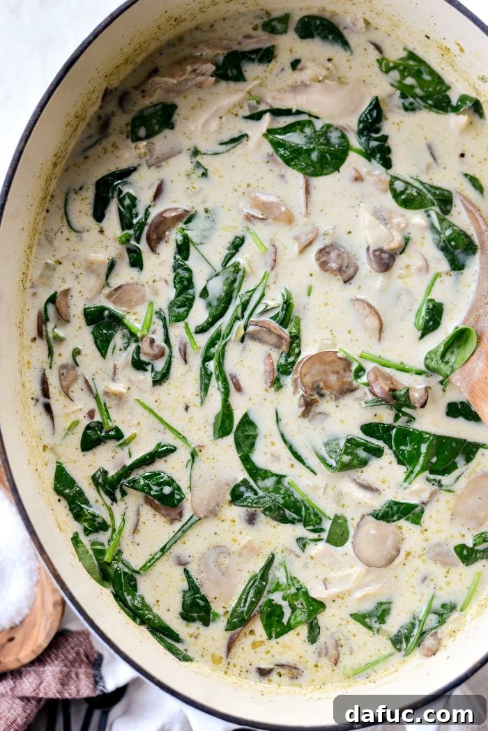 Spinach wilting into the hot Chicken Forester Soup, blending with the chicken and mushrooms