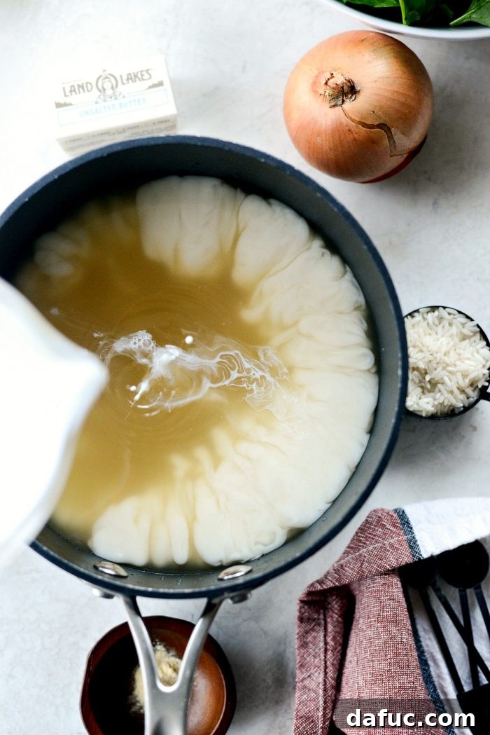 Warming broth, water, and half & half in a saucepan for creamy chicken soup