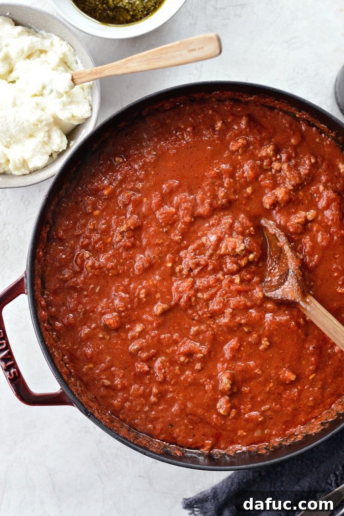 Assembling ingredients: meat sauce, pasta, pesto, ricotta, and mozzarella