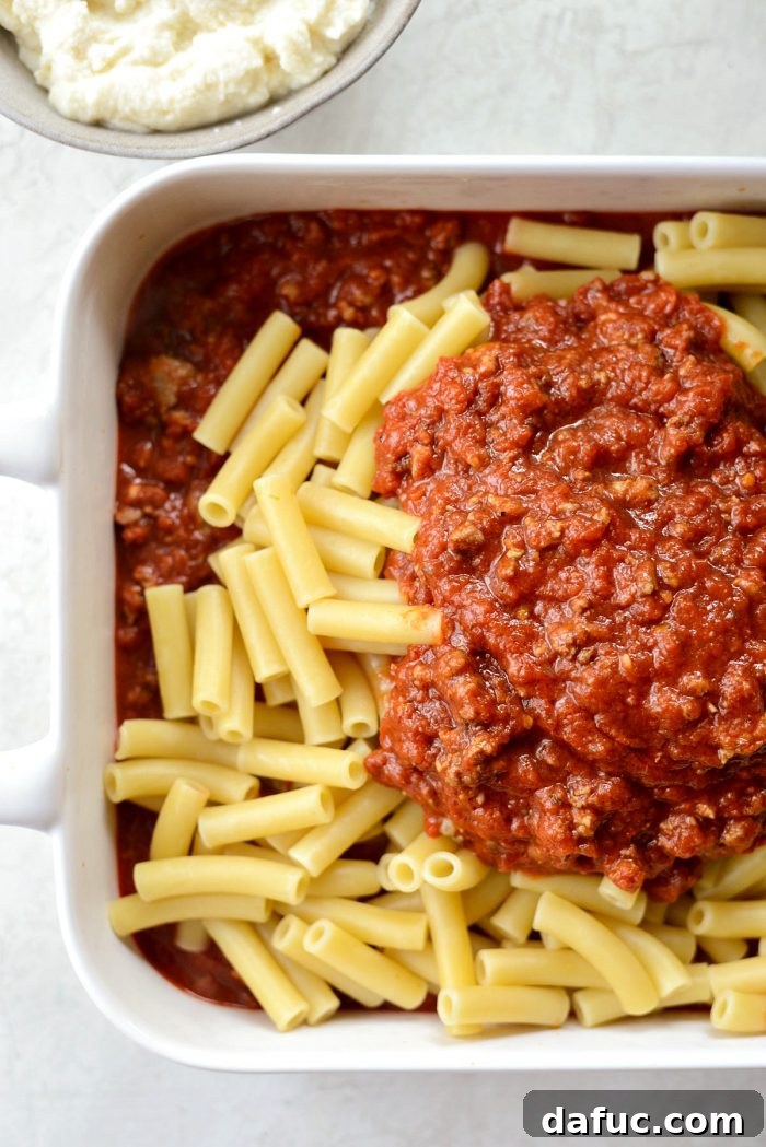 Adding a layer of ziti pasta over the meat sauce