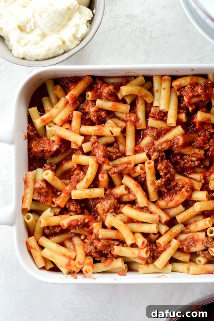 Tossing pasta with meat sauce for the middle layer