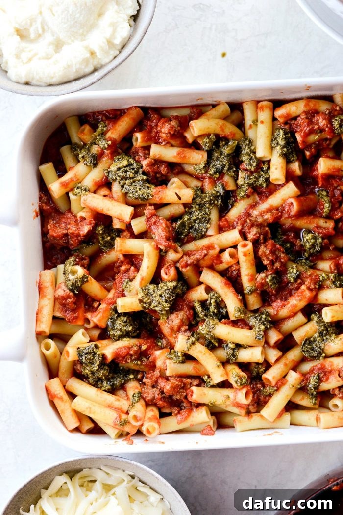 Drizzling basil pesto over the pasta layer