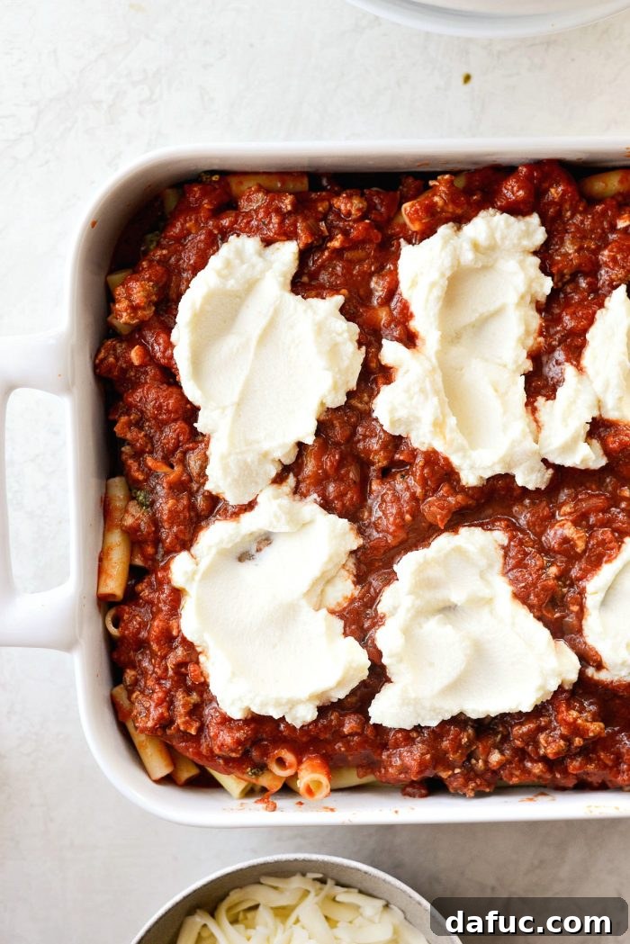 Adding dollops of creamy ricotta cheese over the meat sauce