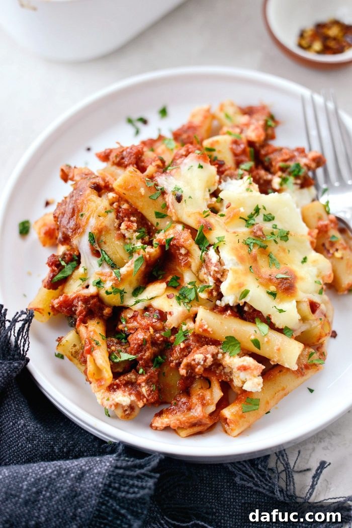 A large serving spoon scooping Spicy Italian Sausage Baked Ziti