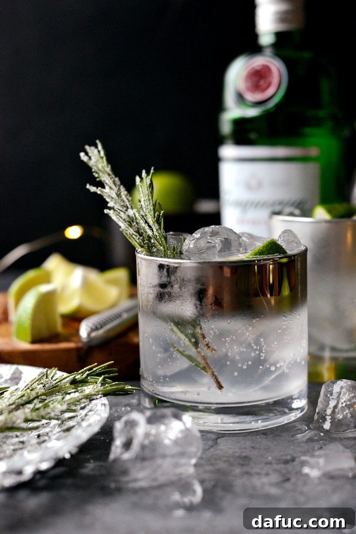 A vibrant, well-lit Classic Gin and Tonic with sugared rosemary, ready to be enjoyed in a festive setting.