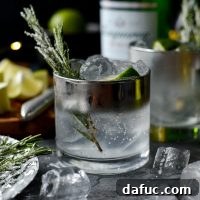 Classic Gin and Tonic garnished with sugared rosemary and lime, a festive holiday drink.