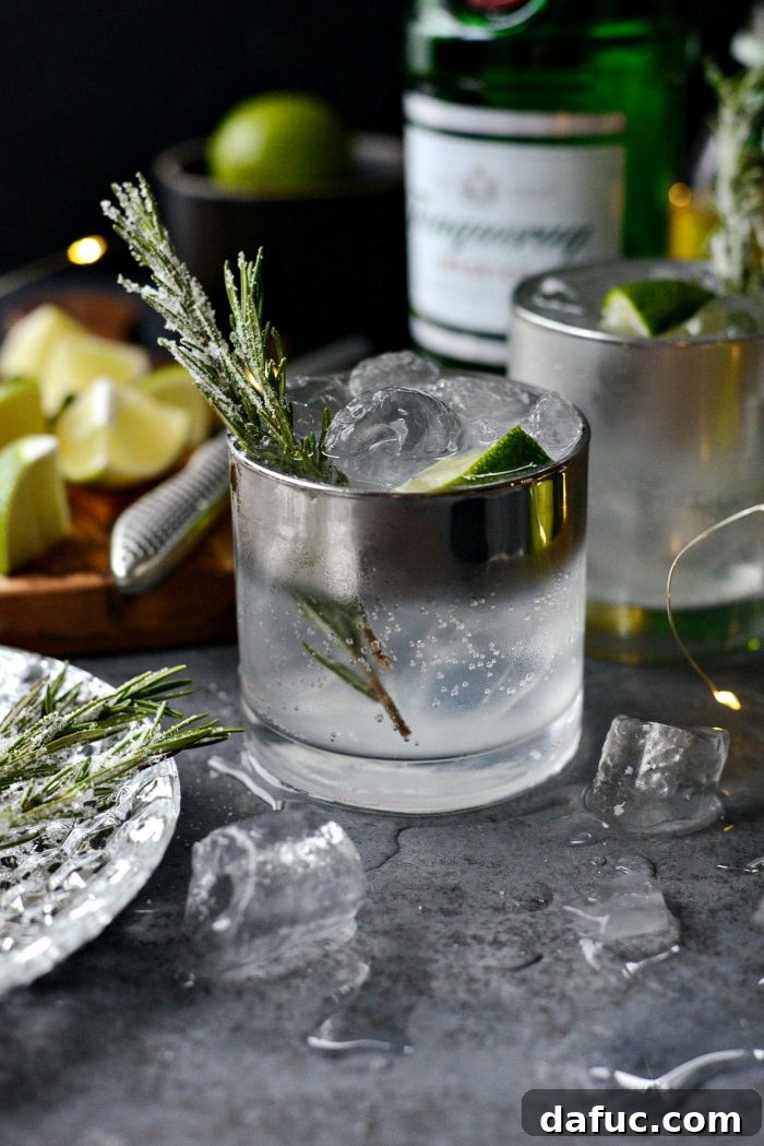 An overhead shot of a Classic Gin and Tonic with sugared rosemary garnish and lime, highlighting its refreshing appeal.