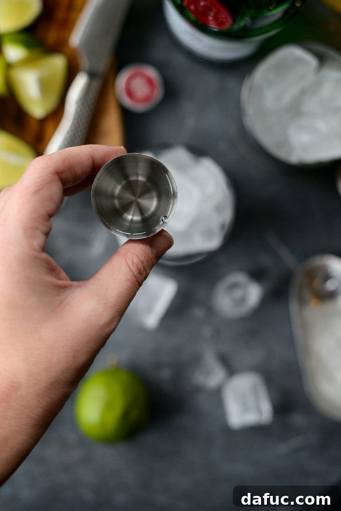 The Perfect Gin and Tonic 5 Bartender filling a highball glass with ice for a Gin and Tonic cocktail, showing the first step in preparation.