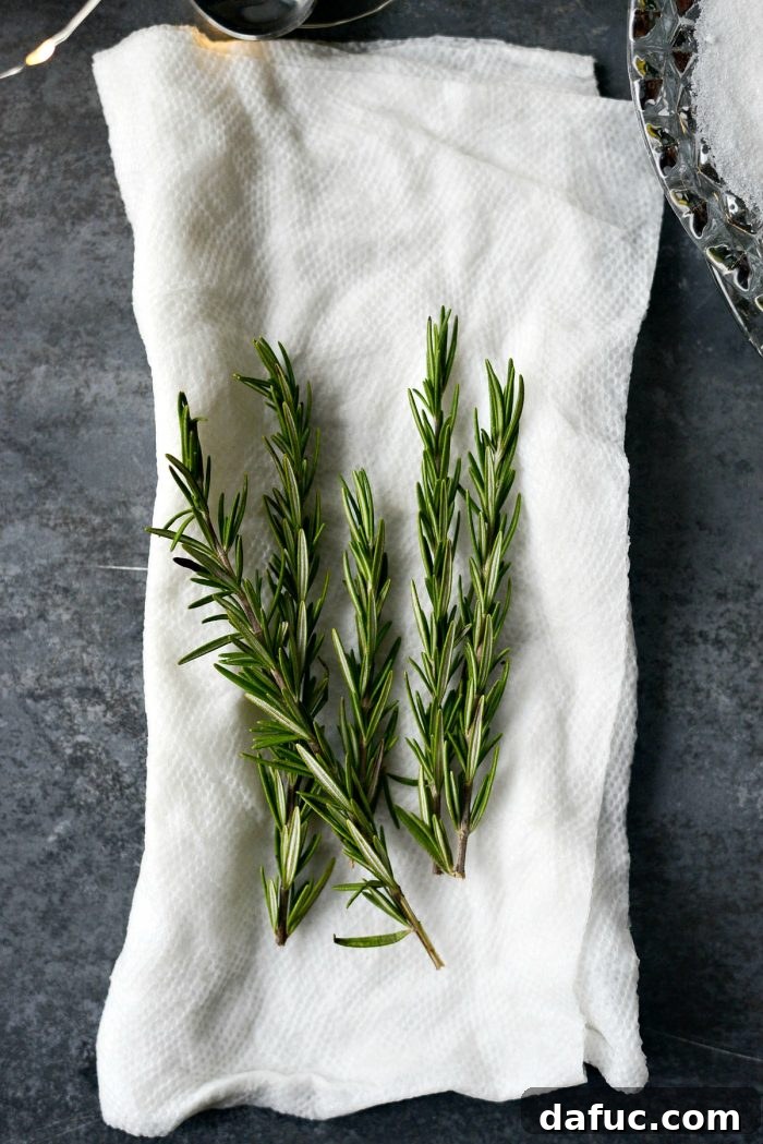 The Perfect Gin and Tonic 8 Ingredients laid out for making sugared rosemary: fresh rosemary, paper towel, and a bowl of fine sugar.