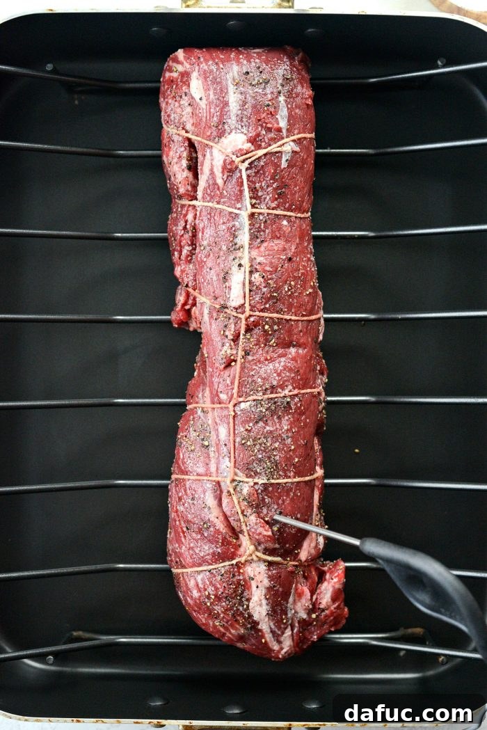 Peppercorn Crusted Beef Tenderloin 6 Placing seasoned beef tenderloin on a roasting rack in a pan.