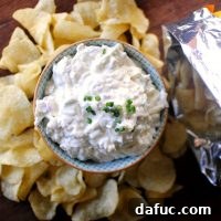 A small square image of the Cheesy Roasted Garlic Chip Dip in a bowl with chips arranged around it, appetizing and ready to eat.