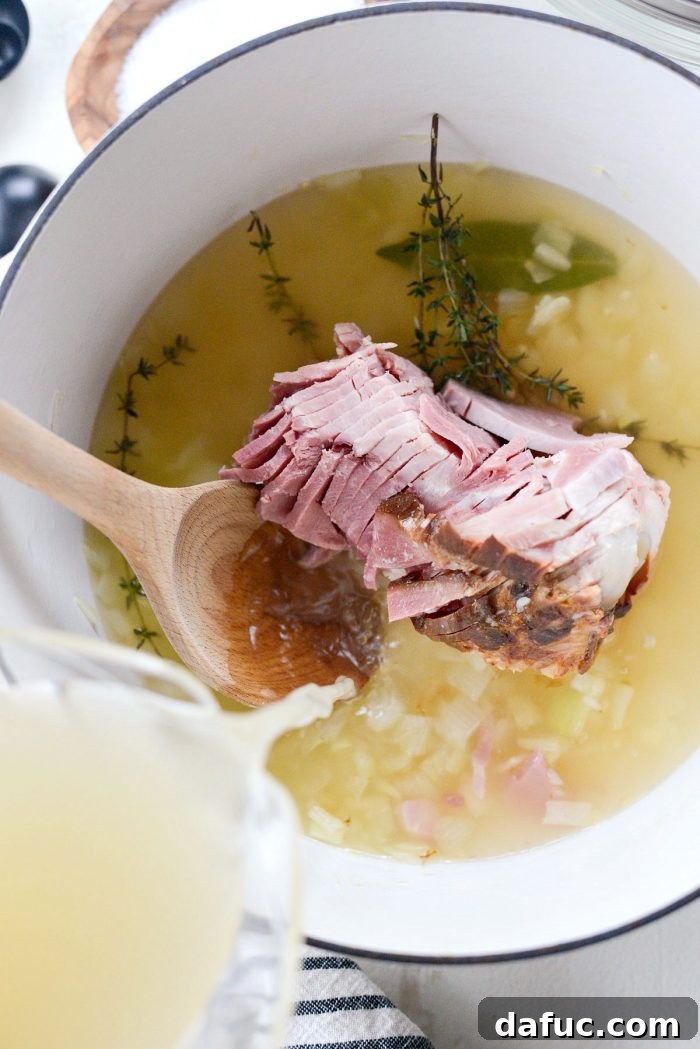 Hearty Ham and White Bean Soup 10 Pouring low-sodium chicken broth over the ham bone and aromatics in the Dutch oven.
