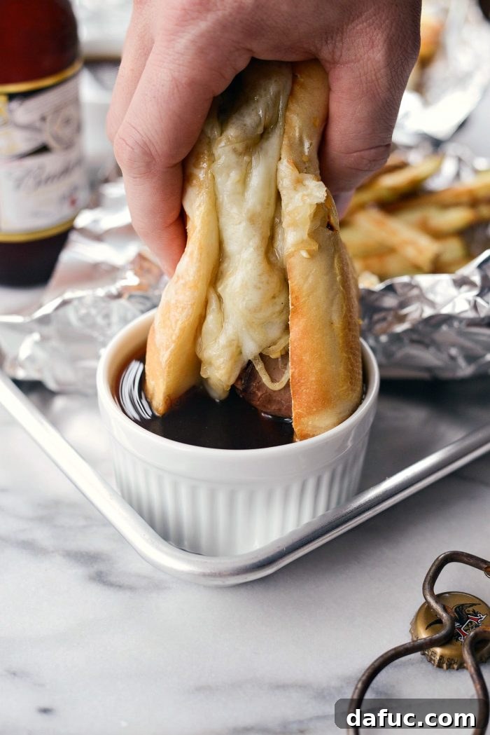 Effortless French Dip Delights 18 A hand dipping a French Dip sandwich into a ramekin of rich au jus