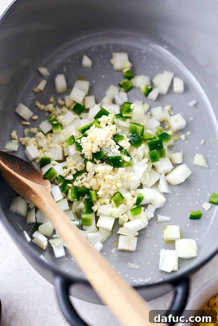 Effortless Chicken Tortilla Soup Delight 4 Fresh ingredients laid out on a wooden cutting board: diced onions, jalapeños, garlic, and a pinch of salt.