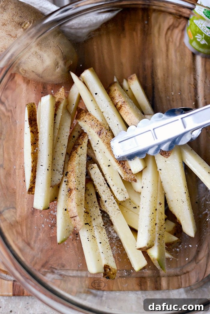 Crispy Homemade Air Fryer Fries 7 Potato fries tossed with olive oil and seasonings in a large mixing bowl