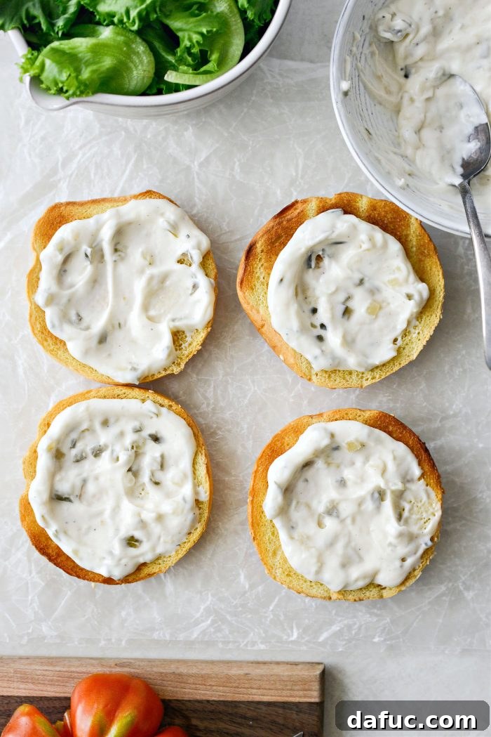 Golden Crispy Fish Sandwiches 19 Spreading homemade tartar sauce on both sides of a toasted bun
