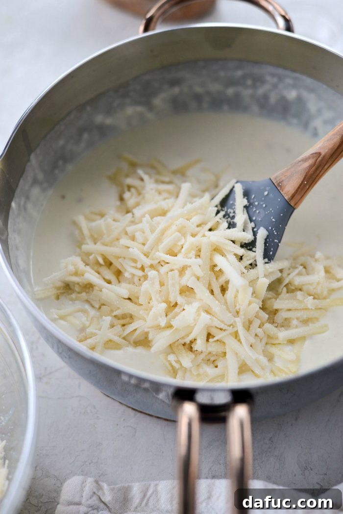 Opulent Lobster Mac and Cheese 12 Creamy white cheese sauce thickening in a saucepan, perfectly seasoned.