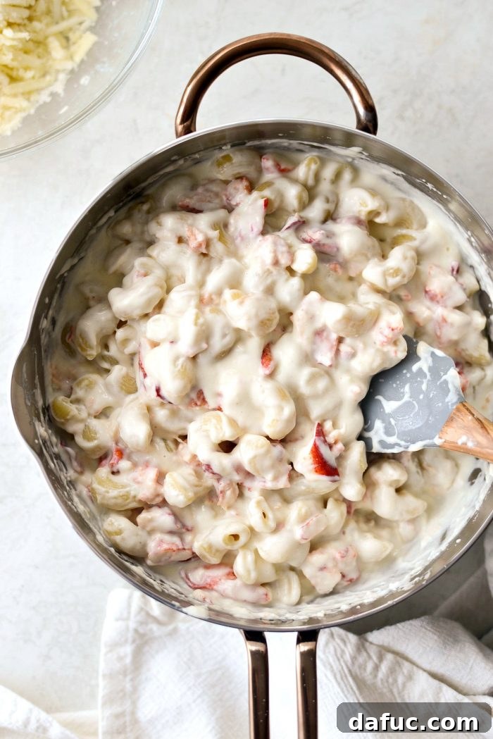 Opulent Lobster Mac and Cheese 17 Chopped lobster meat being added to the pasta and cheese sauce mixture.