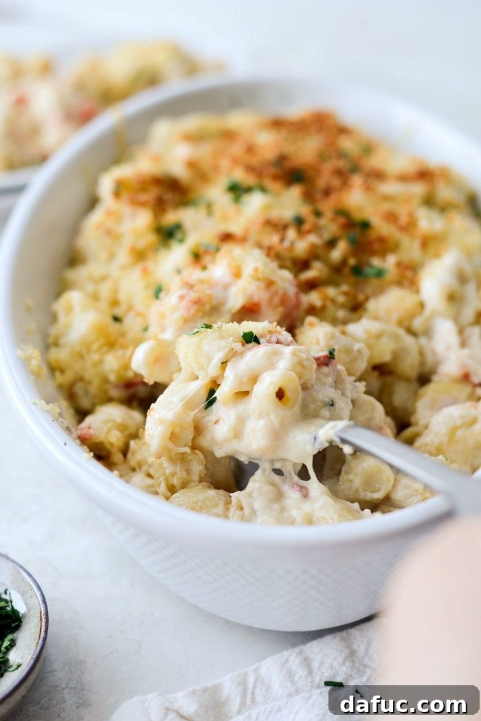 Opulent Lobster Mac and Cheese 3 Close-up shot of cooked lobster pieces and pasta coated in creamy white cheese sauce, ready for baking.