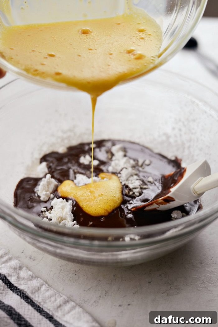 Pouring the warm, melted chocolate mixture into the bowl containing sifted dry ingredients