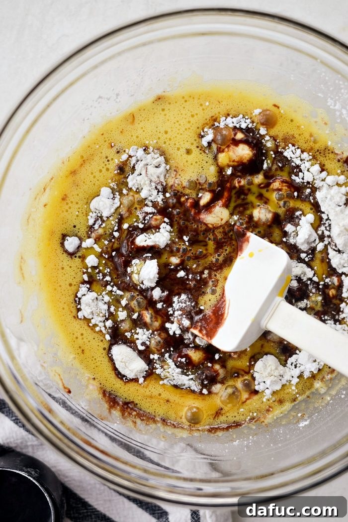Adding the frothy, beaten eggs to the combined chocolate and flour mixture for the lava cake batter