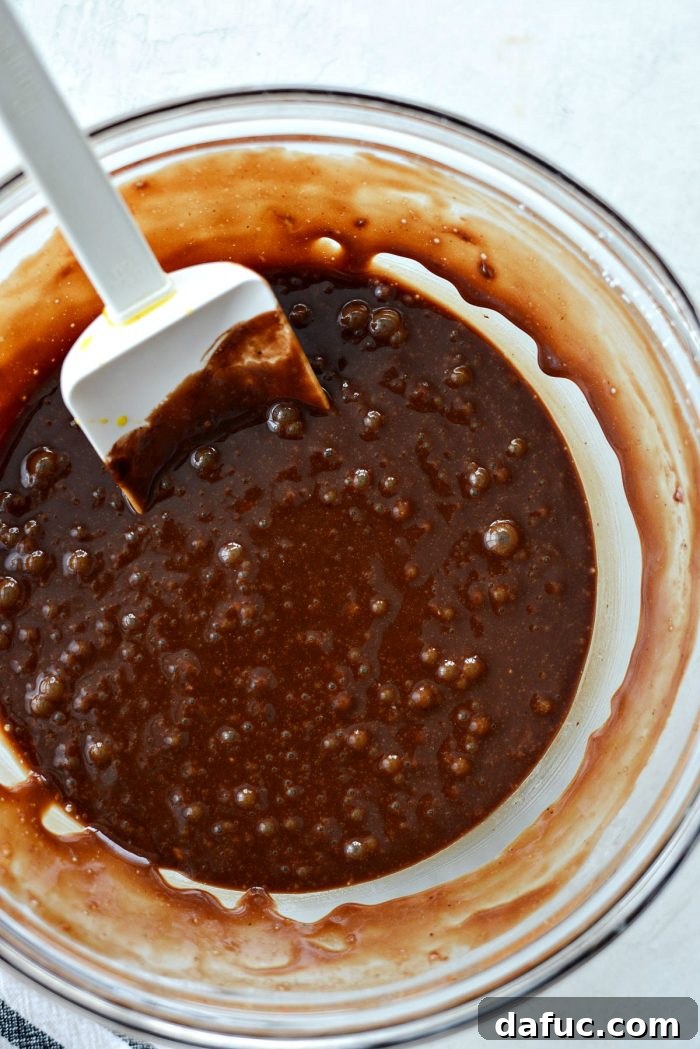 Gently stirring the molten chocolate lava cake batter with a rubber spatula until just combined