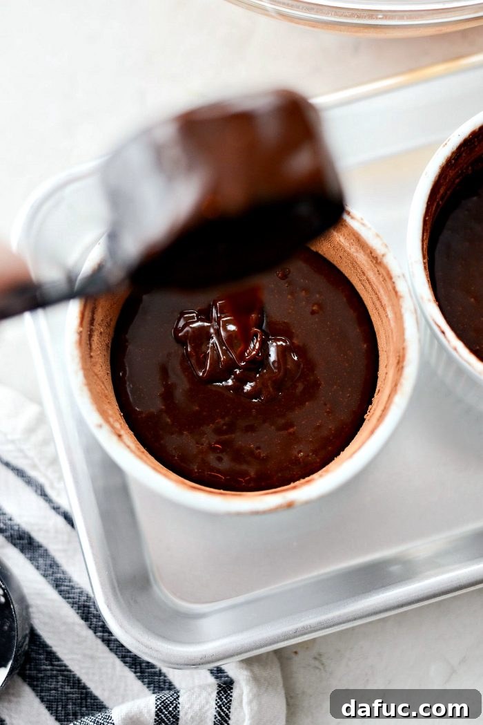 Molten chocolate lava cake batter divided evenly into two prepared ramekins on a baking sheet, ready for oven