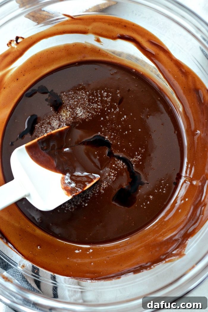 Whisking the melted chocolate and butter mixture until it becomes perfectly smooth and glossy