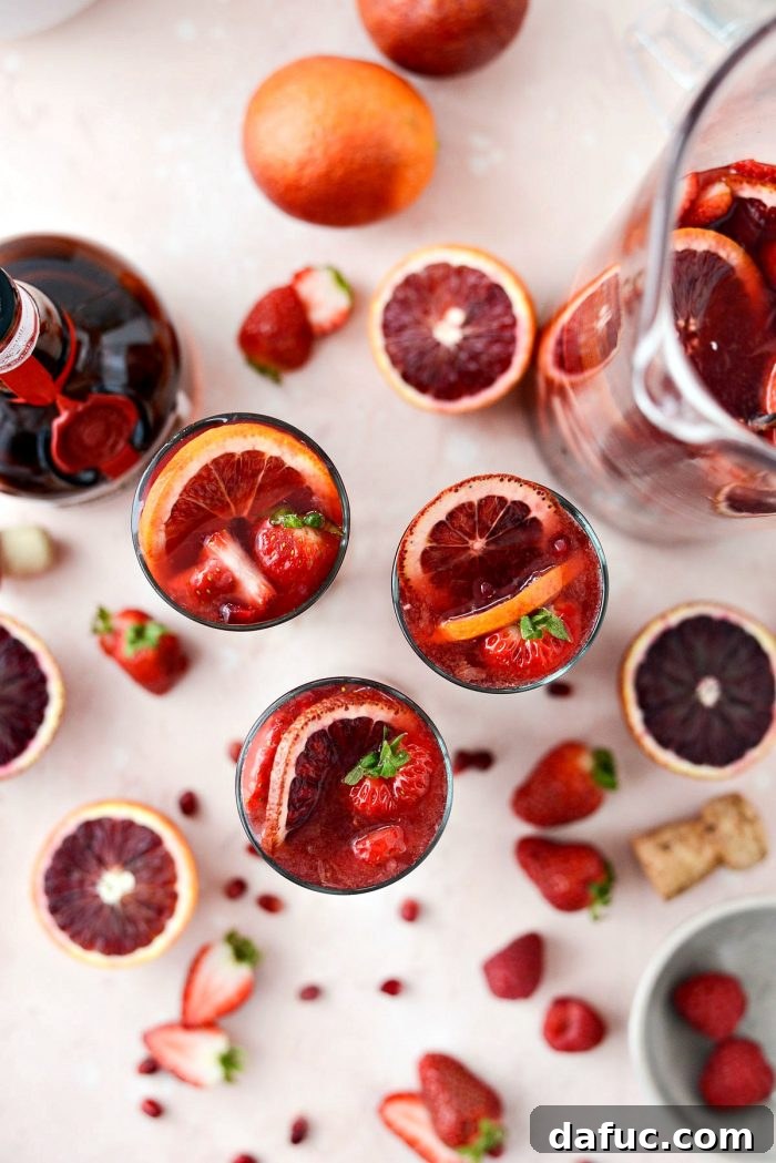 A beautifully presented glass of Champagne Sangria with a garnish of blood orange and fresh berries, perfect for a celebration.