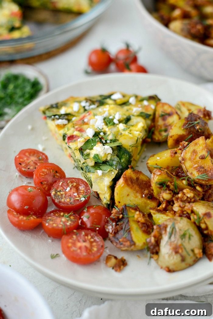 A complete breakfast spread featuring Tomato Spinach and Feta Crustless Quiche with breakfast potatoes and cherry tomatoes.
