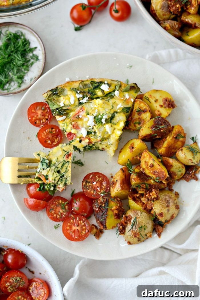 Final plated slice of Tomato Spinach and Feta Crustless Quiche with a side of fresh produce.