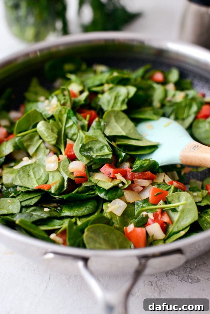 Spinach, roasted red pepper, and tomato added to the skillet to wilt.