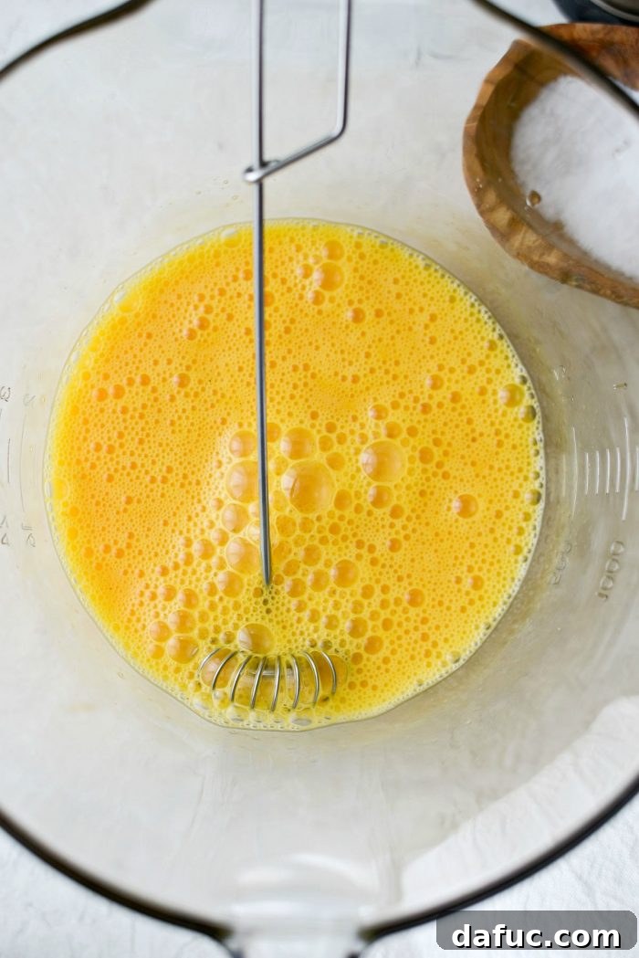 Six eggs cracked into a mixing bowl, seasoned with salt and pepper.