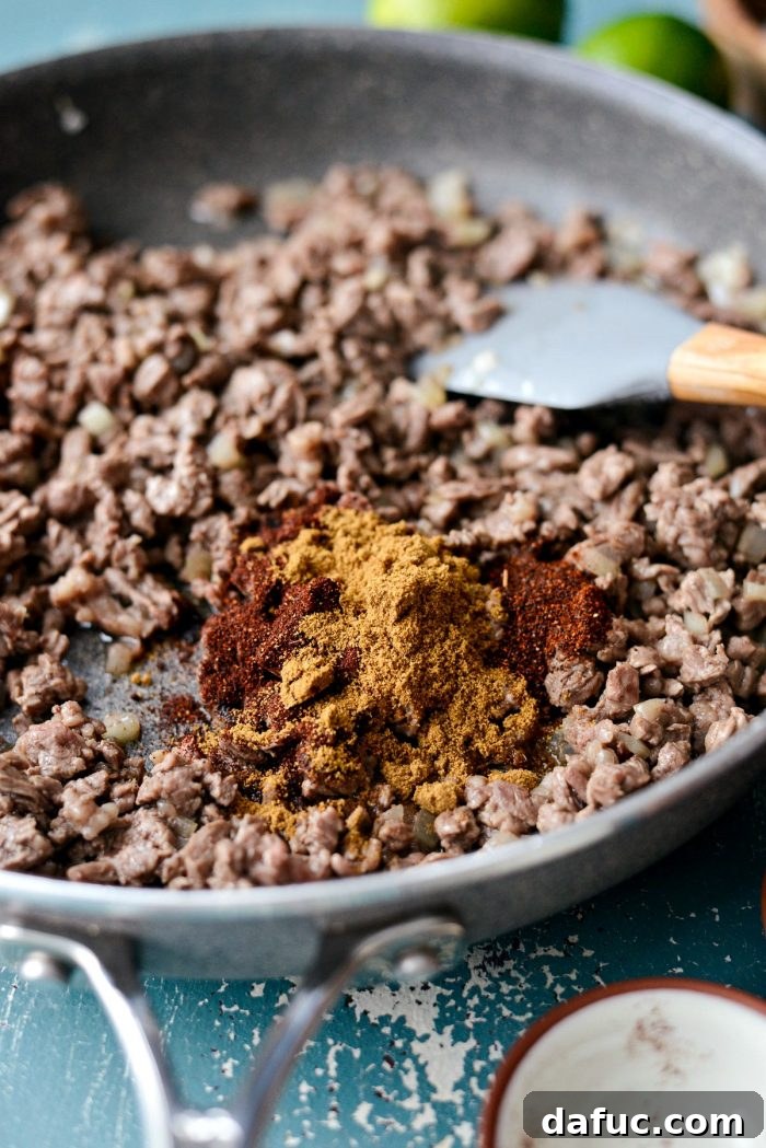 Cooking minced skirt steak and diced yellow onion in a skillet for Easy Beef Street Tacos. SimplyScratch.com recipe.