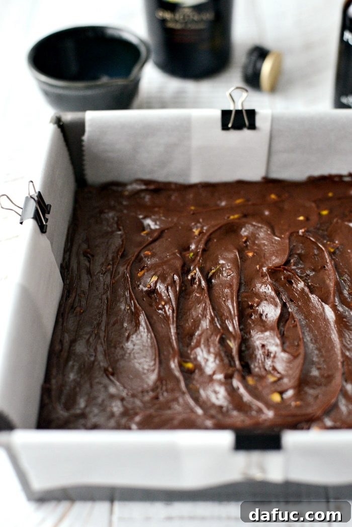 Baileys Chocolate Pistachio Fudge mixture being transferred to a lined pan.