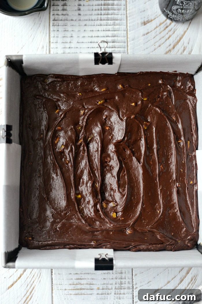 Baileys Chocolate Pistachio Fudge smoothed in a pan with an offset spatula.
