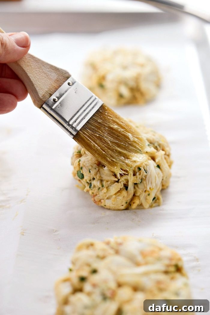 Golden Baked Maryland Crab Delights 14 Eight raw crab cakes, gently shaped and brushed with butter, on a parchment-lined baking sheet.