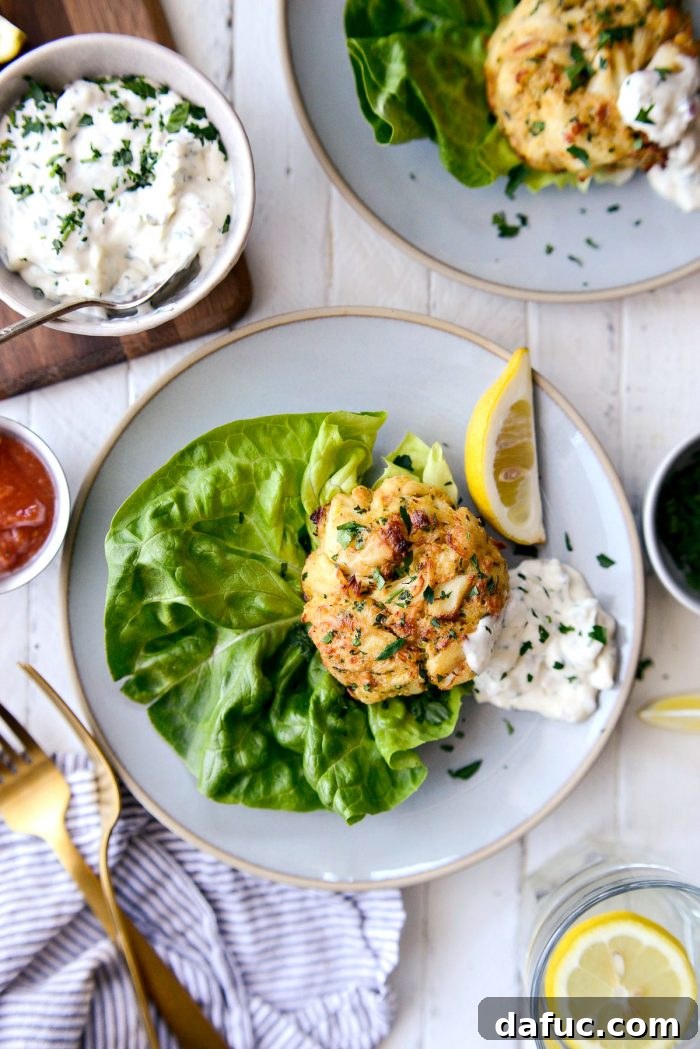 Golden Baked Maryland Crab Delights 19 A hand gently squeezing lemon juice over a freshly baked Maryland crab cake.