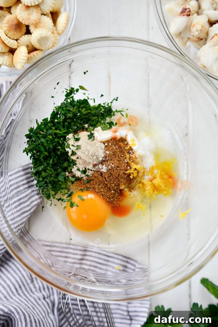 Golden Baked Maryland Crab Delights 8 Mixing bowl with wet ingredients for crab cakes, including mayonnaise, yogurt, and egg.