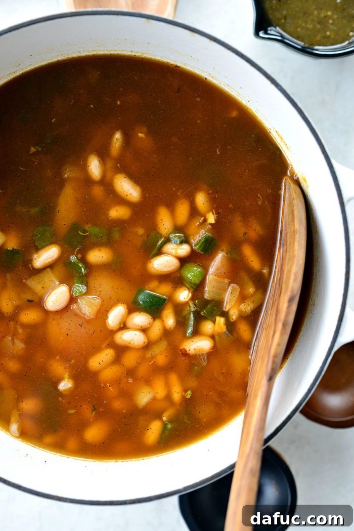 Hearty Poblano Chicken and White Bean Stew 13 Low-sodium chicken broth being poured into the pot with chicken, beans, and vegetables