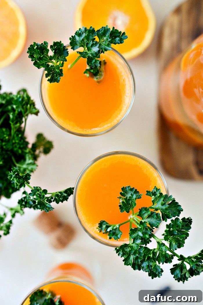 Golden Glow Mimosa 12 A beautifully composed flat lay of Carrot Orange Mimosas, garnished with parsley, alongside fresh carrots and oranges, emphasizing the natural ingredients.