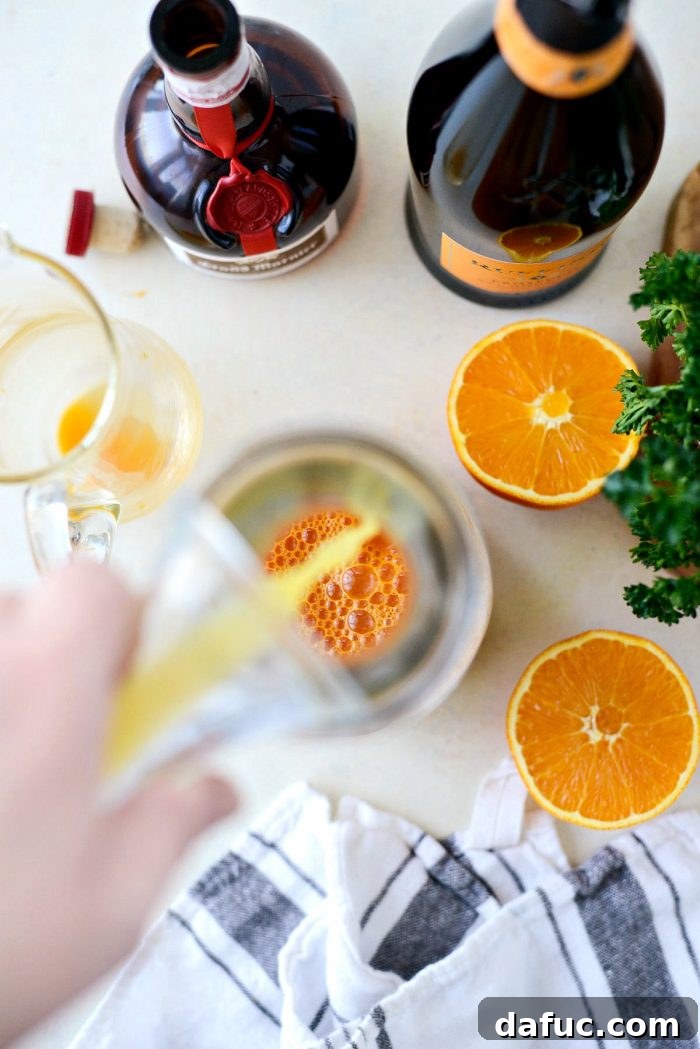 Golden Glow Mimosa 6 Pouring 2 cups of vibrant, chilled carrot juice into a clear glass pitcher, the first step in making Carrot Orange Mimosas.
