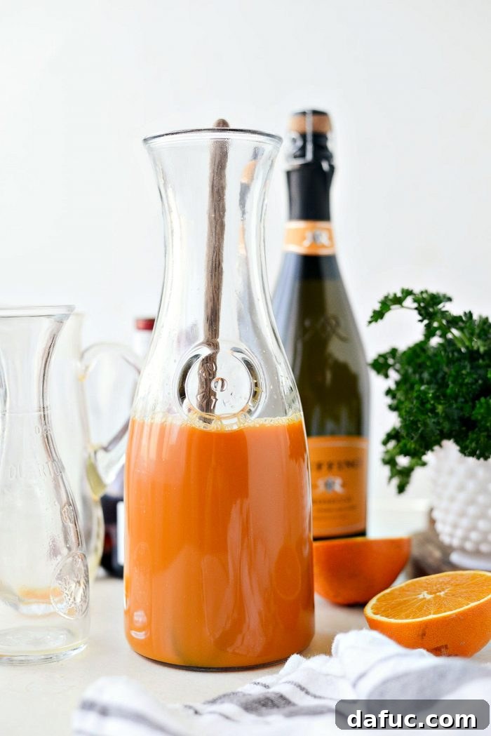 Golden Glow Mimosa 7 Adding 1.5 cups of fresh orange juice and 0.25 cup of Grand Marnier to the pitcher already containing carrot juice, creating the base for the mimosa.